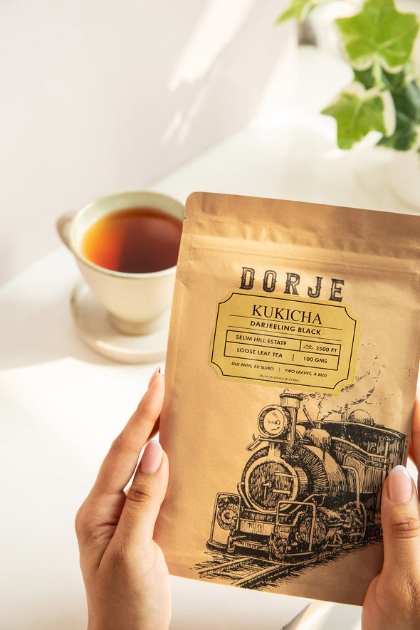 A pair of hands holding a packet of Darjeeling Kukicha Tea