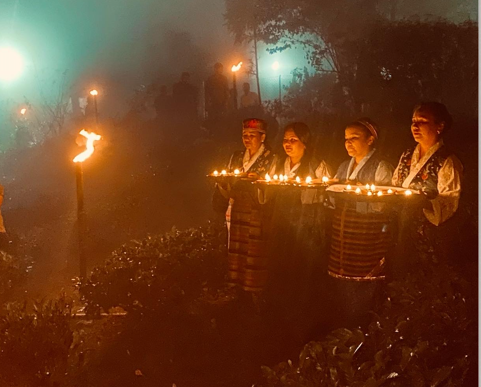 a row of woman holding diyas for moonlight plucking tea ceremony